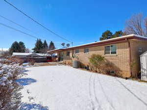 Snow covered back of property with brick siding