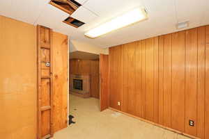 Finished below grade area featuring light flooring, a fireplace, and wood walls