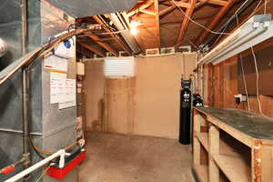 Unfinished basement featuring heating unit, a workshop area, and a water softener