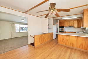 Kitchen featuring light countertops, a peninsula, stainless steel oven, wood finish cabinetry, and ceiling fan