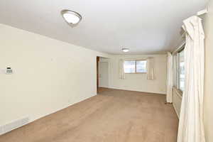 Empty room featuring light carpet and baseboards