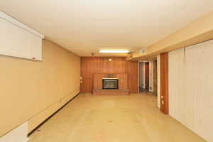Finished below grade area with light flooring, wooden walls, and a brick fireplace