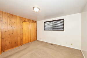 Carpeted empty room with wooden walls and baseboards