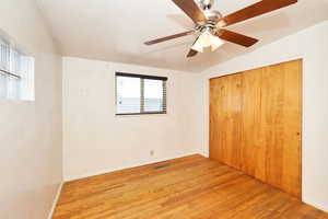 Unfurnished bedroom featuring light wood finished floors, vaulted ceiling, a ceiling fan, and a closet