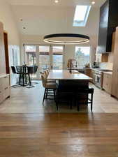Dining area featuring a skylight, healthy amount of natural light, light wood-style floors, lofted ceiling, and french doors