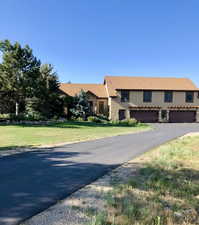 Mediterranean / spanish house featuring stucco siding, asphalt driveway, a front yard, and a garage