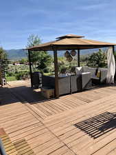 Wooden terrace featuring outdoor furniture, a gazebo, and a mountain view