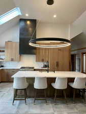 Kitchen featuring a kitchen bar, lofted ceiling, a center island with sink, open shelves, and modern cabinets