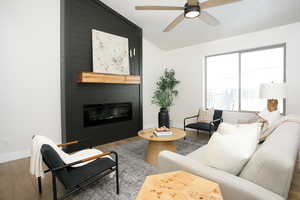 Living area with vaulted ceiling, a fireplace, wood finished floors, and ceiling fan