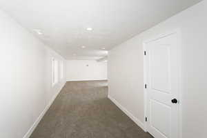 Hallway with dark carpet and recessed lighting