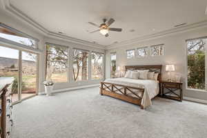 Bedroom with a mountain view, access to exterior, light carpet, a raised ceiling, and ceiling fan