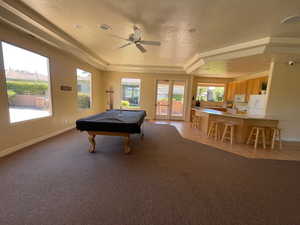Playroom with pool table, ceiling fan, a tray ceiling, and a textured ceiling