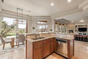Kitchen with a tray ceiling, a center island with sink, light stone counters, open floor plan, and stainless steel dishwasher