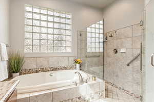Full bath featuring a walk in shower, a garden tub, and vanity