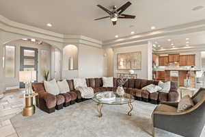 Living area featuring a tray ceiling, a ceiling fan, recessed lighting, and arched walkways
