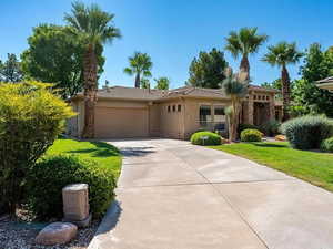 View of front facade with an attached garage, stucco siding, driveway, and a front yard