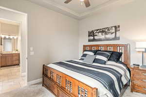 Bedroom with light colored carpet, a ceiling fan, and ensuite bathroom