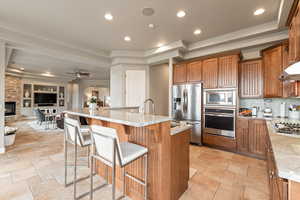 Kitchen featuring a tray ceiling, recessed lighting, wood finish cabinets, a breakfast bar, and stainless steel appliances