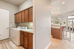 Laundry room featuring cabinet space, independent washer and dryer, recessed lighting, and light stone finish flooring