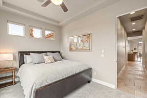 Bedroom featuring a tray ceiling, multiple windows, ceiling fan, light carpet, and recessed lighting