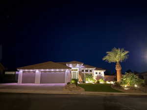 View of front facade with an attached garage, driveway, a yard, and a tiled roof