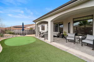 Fenced yard with outdoor lounge area, a patio area, and a putting area