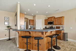 Kitchen with dark countertops, a breakfast bar area, wood finish cabinets, arched walkways, and tasteful backsplash