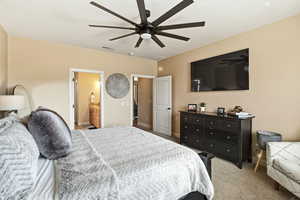 Bedroom featuring light carpet, connected bathroom, and ceiling fan