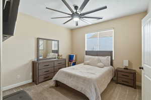 Bedroom with a ceiling fan and light colored carpet