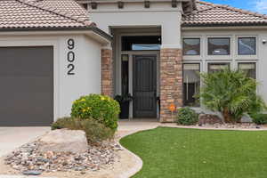 Property entrance with a tiled roof, stucco siding, and stone siding