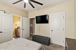 Carpeted bedroom with ceiling fan and connected bathroom