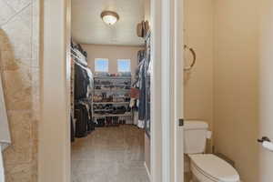 Bathroom with a walk in closet and light carpet