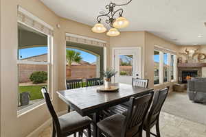 Dining area with a stone fireplace, stone tile flooring, and suspended lighting