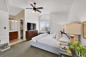Bedroom with vaulted ceiling, carpet flooring, a ceiling fan, a walk in closet, and tile patterned floors