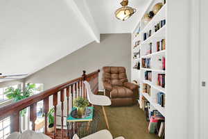 Sitting room with dark carpet, vaulted ceiling with beams, and a ceiling fan