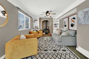Living room with built in features, ornamental molding, a wood stove, and a ceiling fan
