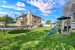 Back of house with a trampoline, a chimney, and a fenced backyard
