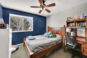 Bedroom with wallpapered walls, an accent wall, carpet flooring, ceiling fan, and a textured ceiling