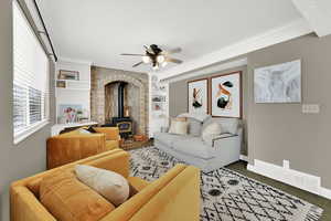 Carpeted living room featuring a wood stove, built in features, a ceiling fan, and ornamental molding