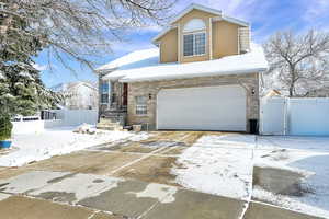 Traditional home with brick siding, concrete driveway, a gate, and an attached garage