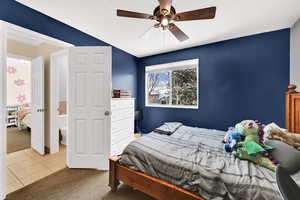 Carpeted bedroom with a ceiling fan, ensuite bathroom, and a textured ceiling
