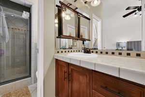 Bathroom featuring a stall shower, vanity, and a ceiling fan