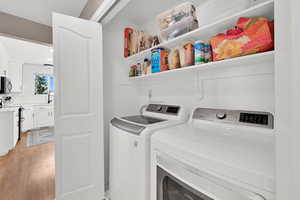 Laundry area featuring light wood-type flooring and washer and clothes dryer