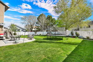 Fenced backyard with a patio area and a trampoline