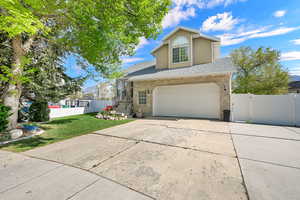 Traditional home with brick siding, a gate, concrete driveway, roof with shingles, and an attached garage