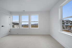 Unfurnished room featuring light colored carpet, plenty of natural light, and a mountain view