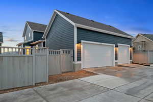 View of property exterior with concrete driveway, a shingled roof, and a garage