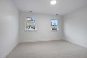 Spare room featuring light carpet and baseboards