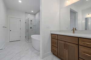Bathroom featuring a marble finish shower, recessed lighting, vanity, light marble finish flooring, and a freestanding bath