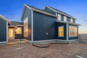 Back of house at dusk featuring a patio and entry steps